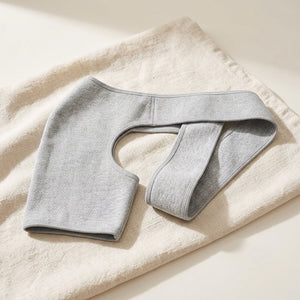 Woman wearing a grey knit compression shoulder brace in a kitchen